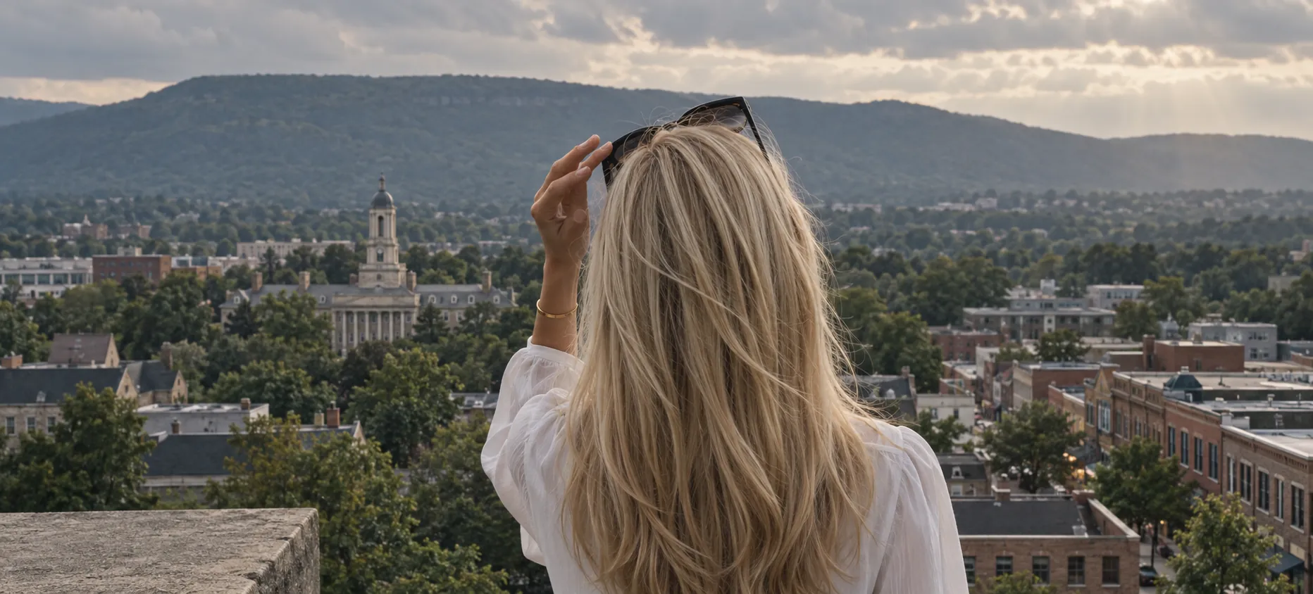 Woman with long blonde hair overlooking State College and Old Main
